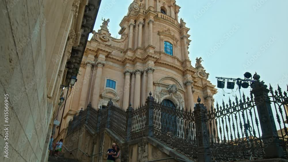 Tourists visiting the Duomo di San Giorgio in Ragusa, Italy. A crowd of people explores the baroque Catholic church with its baroque façade and its imposing scenographic staircase in Ragusa, Italy. Tourists visiting the Duomo di San Giorgio in Ragusa, Italy. A crowd of people explores the baroque Catholic church with its baroque façade and its imposing scenographic staircase in Ragusa, Italy.