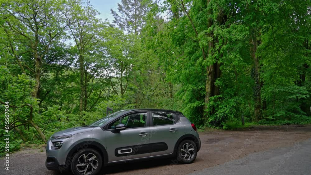 A wide shot of a car stopped roadside in the middle of the forest just outside the village of Betws-y-Coed in Snowdonia National Park, Wales, UK A wide shot of a car stopped roadside in the middle of the forest just outside the village of Betws-y-Coed in Snowdonia National Park, Wales, UK