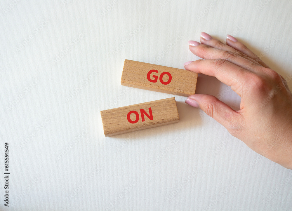 Go on symbol. Wooden blocks with words Go on. Businessman hand. Beautiful white background. Business and Go on concept. Copy space. Go on symbol. Wooden blocks with words Go on. Businessman hand. Beautiful white background. Business and Go on concept. Copy space.