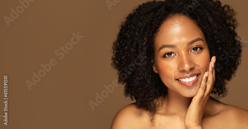 Positive attractive half-naked black lady touching her face