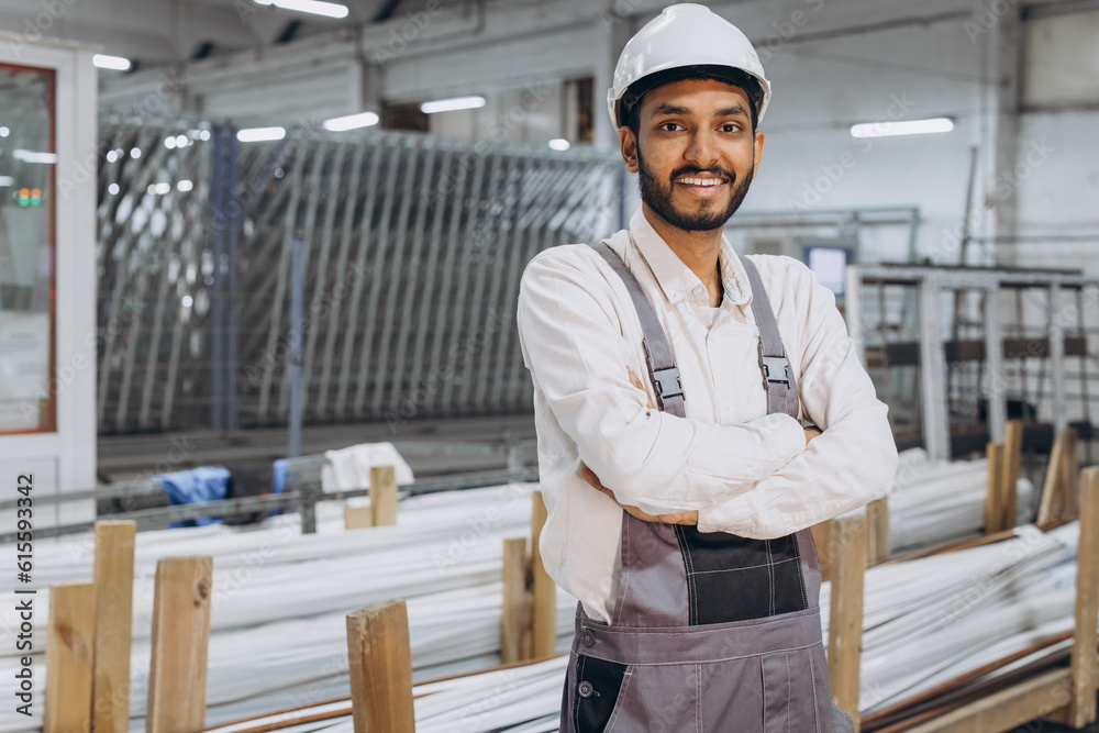 Operator of machine. Industrial worker indoors in factory. Young technician in white hard hat.