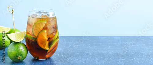 Glass of cold Cuba Libre cocktail on blue background with space for text