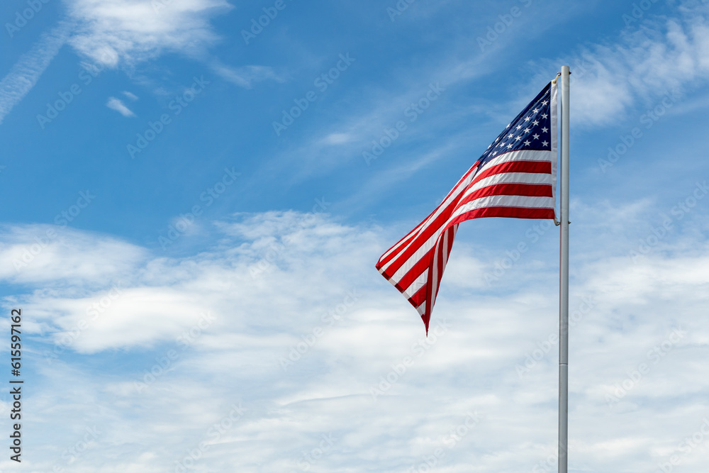 American flag on pole waving against blue sky