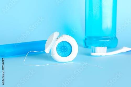 Dental floss and toothbrush on blue background