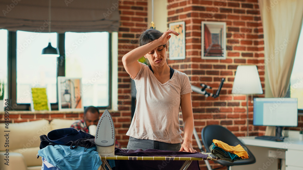 Modern young adult ironing clothes and getting angry at life partner, needing help with household chores. Stressed exhausted girlfriend cleaning apartment and doing housekeeping without man. Modern young adult ironing clothes and getting angry at life partner, needing help with household chores. Stressed exhausted girlfriend cleaning apartment and doing housekeeping without man.