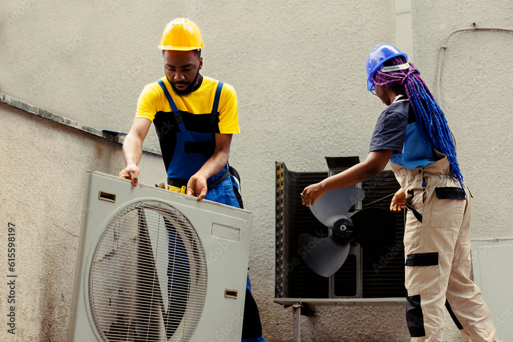 Fototapeta premium African american efficient technicians disassembling hvac system panel with industry techniques and equipment to repair air filters, refrigerant leaks and frozen evaporator coils