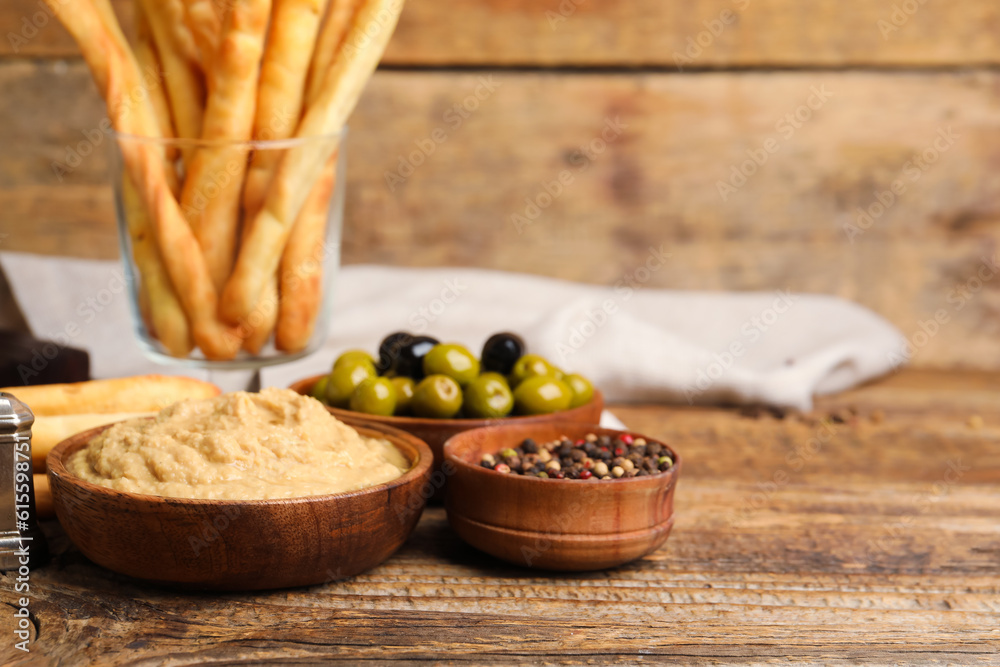 Bowl with tasty hummus on wooden background