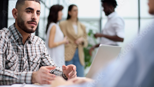 Young adult caucasian male, hiring manager, sits at a desk in a modern office