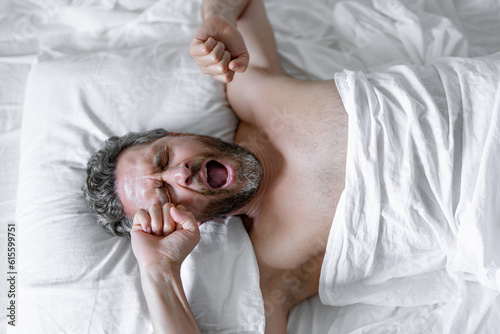 Foto Man yawning waking up in white bed