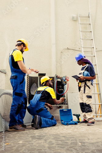 Diverse team of seasoned wiremen mending condenser unit electrical problems caused by bad wiring or broken evaporator coil requiring professional intervention to diagnose and repair. photo