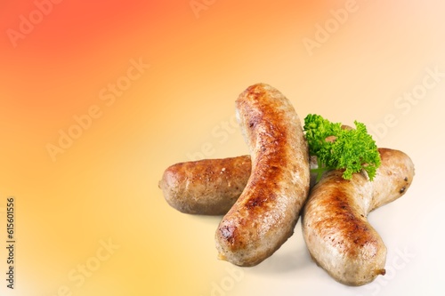 Grilled cooked sausages on color background