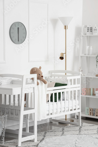 Interior of light bedroom with baby crib, changing table and shelving unit © Pixel-Shot