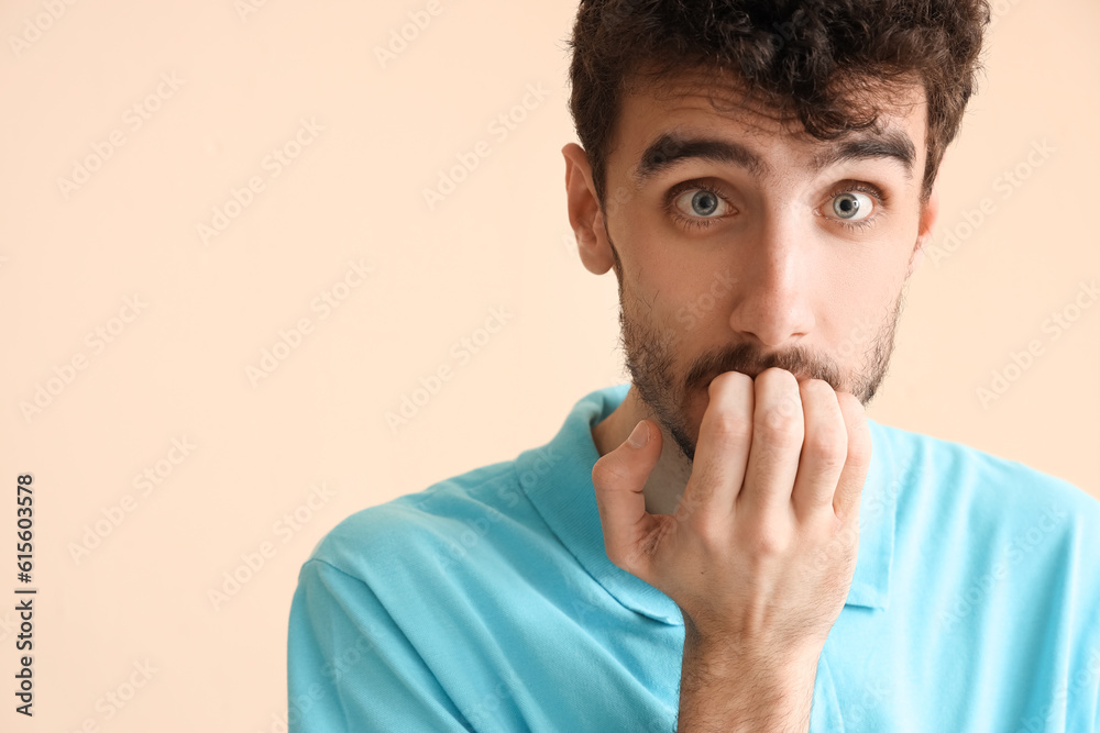 Young man having panic attack on beige background