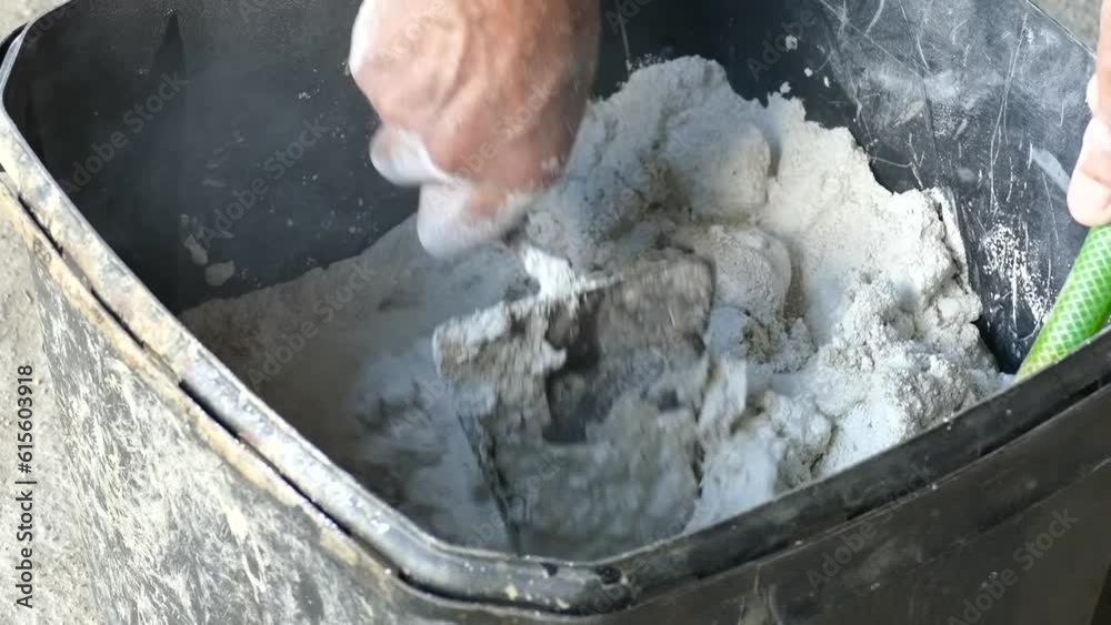 Persona haciendo masa de cemento con una herramienta de trabajo o espátula