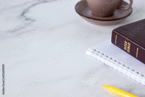 Holy bible, notebook, cup of coffee and marker on white table. Copy space. A close-up. Biblical studying, writing, learning concept. 