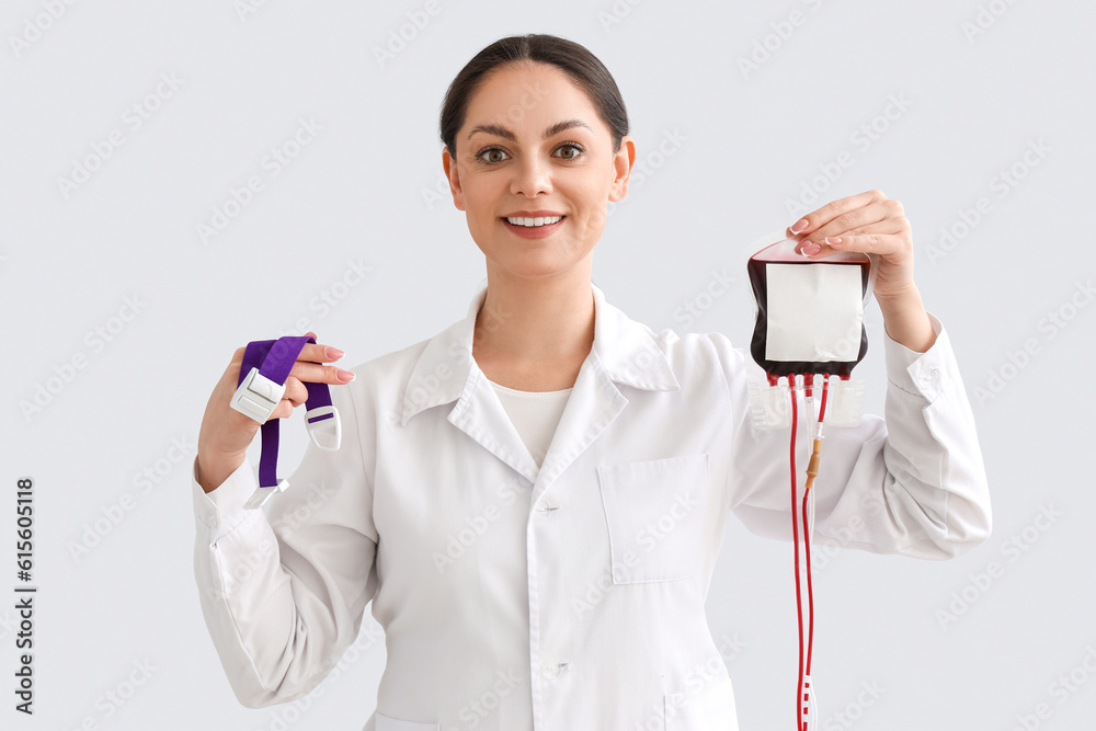Female doctor with elastic belt and blood pack on light background Female doctor with elastic belt and blood pack on light background