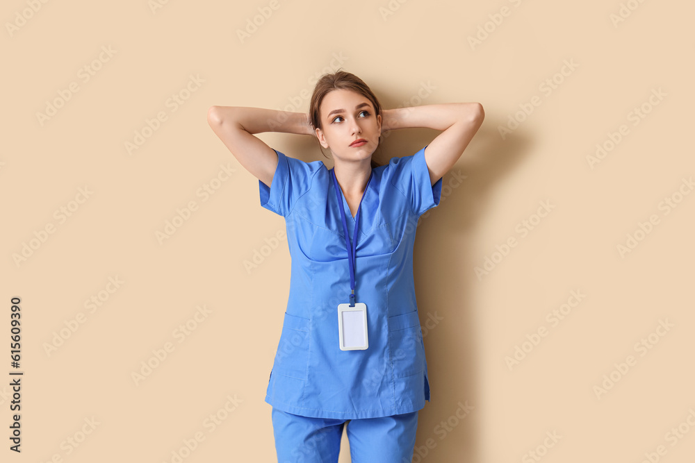 Tired female medical intern on beige background Tired female medical intern on beige background