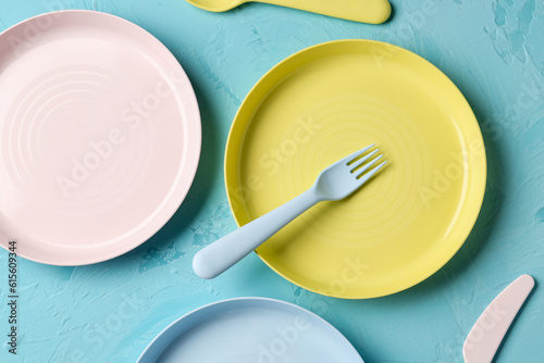 Colorful plates with eating utensils for baby on grunge blue background