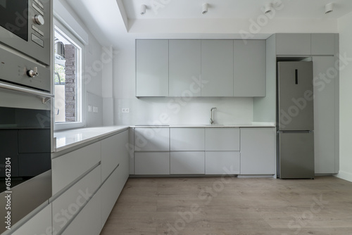 Newly installed modern kitchen covering two walls in an L shape with gray cabinets  white stone countertops