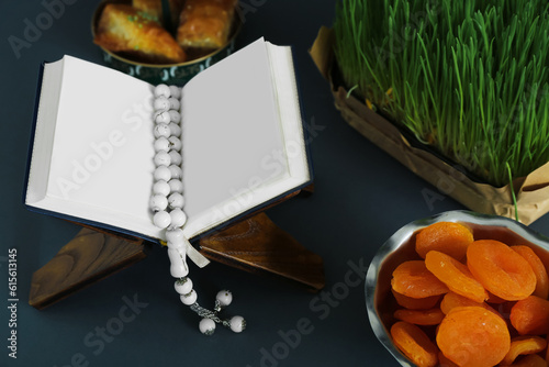 Koran, tasbih, dried apricots and grass on dark background, closeup. Islamic New Year celebration photo