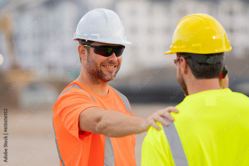 Construction site workers in a helmet work hard. Two workers in a hard hat is responsible for ensuring safety while constructing buildings. Builders workers personal protective equipment. Construction site workers in a helmet work hard. Two workers in a hard hat is responsible for ensuring safety while constructing buildings. Builders workers personal protective equipment.