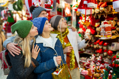 Friendly family with teenage children who came to the Christmas fair in the open air, chooses Christmas souvenirs and toys