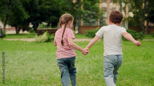 Child Boy girl holding hands play run on green grass. Children play park. Brother sister run together outdoor. Little children dream of flying. Children play, nature. Happy children run to their mom