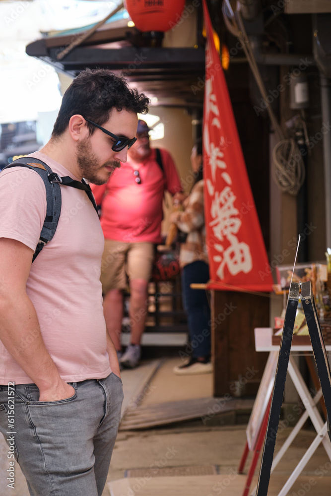 Φωτογραφία European tourist looking at restaurant menu in a traditional street in Miyajima, Hiroshima, Japan