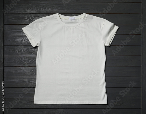 Stylish white T-shirt on gray wooden table, top view