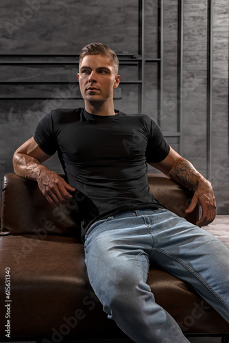 Athletic sexy man in black t-shirt and jeans posing in studio © Vitalii But