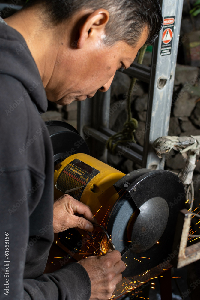 Refining the Weld: Blacksmith Grinding Metalwork with Bench Grinder in Workshop