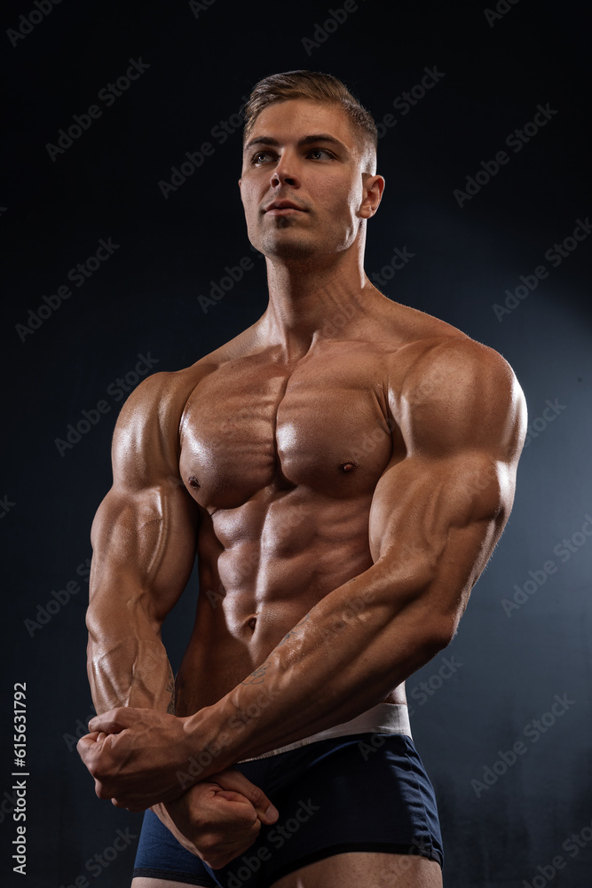 Athletic shirtless man folds his arms, showing pectoral muscles