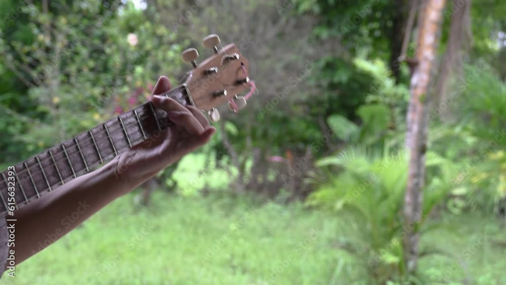 closeup of hands playing string instrument in the field closeup of hands playing string instrument in the field
