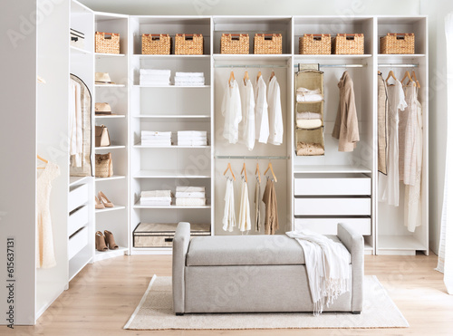 A cozy bedroom with white walls and a closet, featuring clothes hung up in neat fashion photo