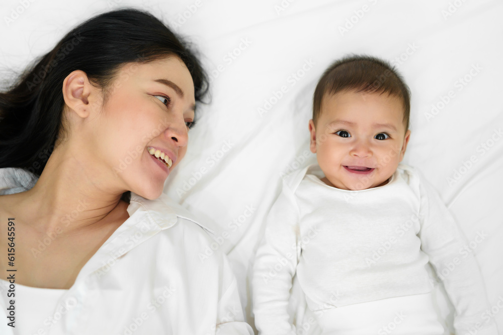 happy mother lying with her infant baby on bed (top view) happy mother lying with her infant baby on bed (top view)