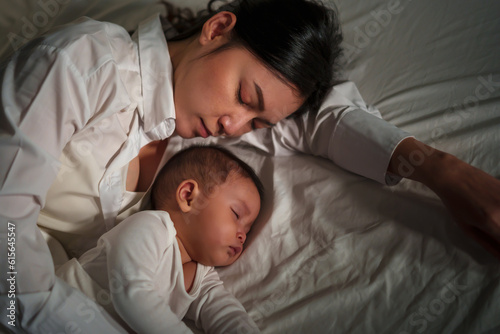 mother embraces the infant baby sleeping together in bed at night