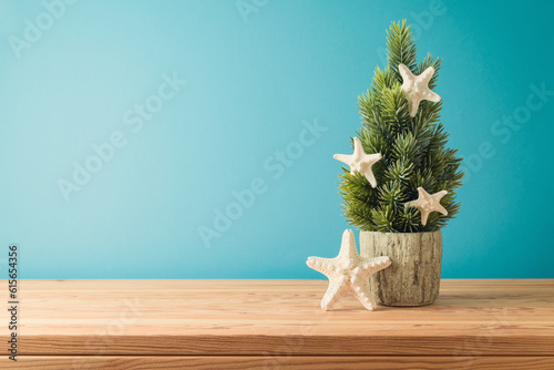 Christmas in July concept with Christmas tree and  starfish on wooden table over blue background