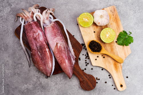 Fresh raw octopus on wooden chopping board background Seafood squid with lemon top view and copy space for your text