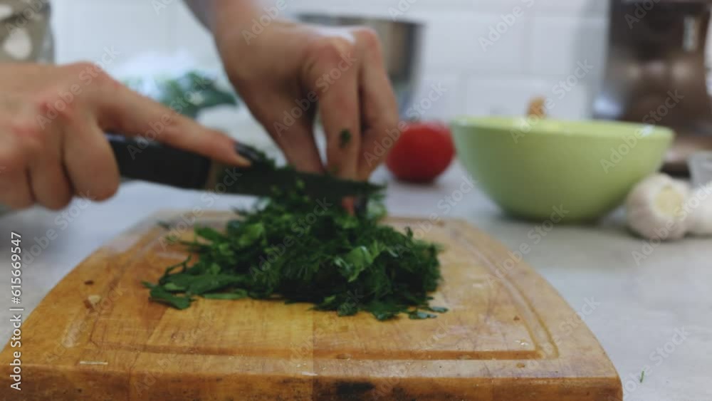 Chop the parsley on a board, greens for the dish. close-up process Chop the parsley on a board, greens for the dish. close-up process