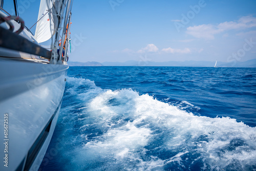 Yacht sailing in an open sea. Close-up view of side of the boat. Clear sky after the rain, waves and water splashes © dtatiana