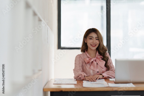 Smiling Asian Accountant person analyze financial report and studies annual figures, analyzes profits
