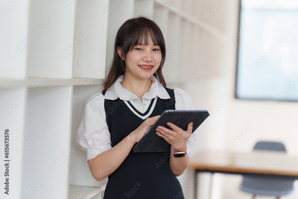 Online education, e-learning. Asian woman in stylish casual clothes, studying using a laptop, listening to online lecture, taking notes, online study at home Online education, e-learning. Asian woman in stylish casual clothes, studying using a laptop, listening to online lecture, taking notes, online study at home