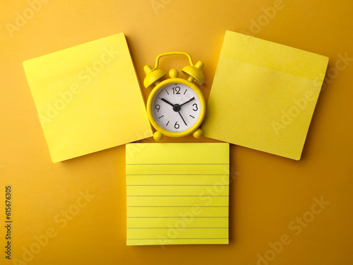 Top view yellow sticky note with alarm clock on a yellow background