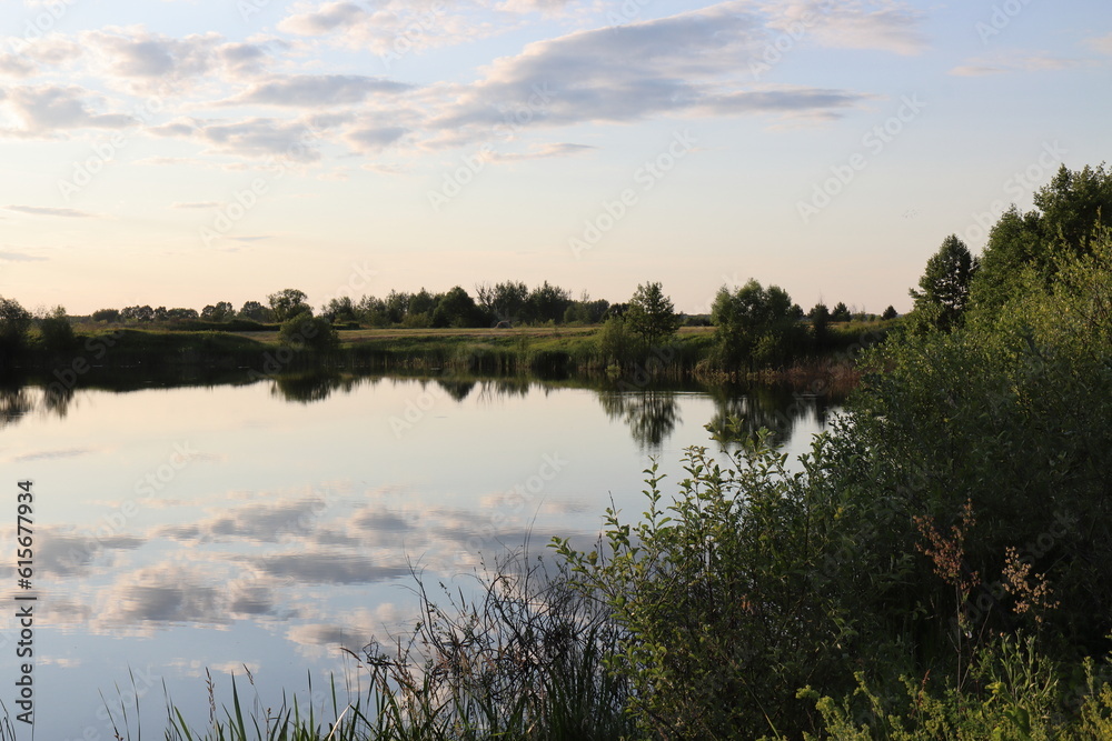 Fototapeta premium Reflections of clouds and trees in the mirror of the water of the lake