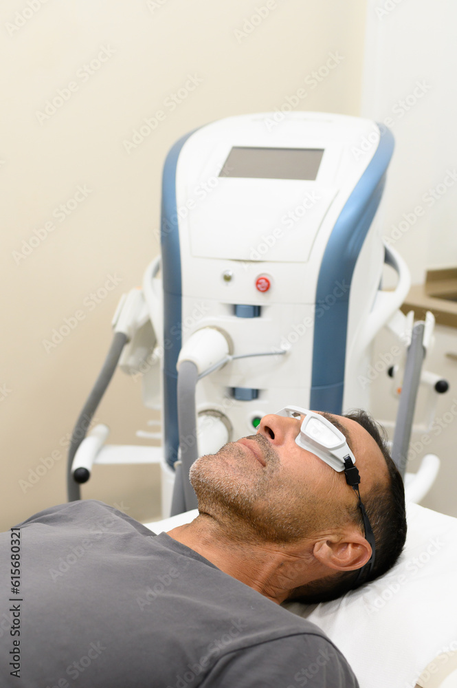Man in protective goggles lying on bed in treatment room Man in protective goggles lying on bed in treatment room