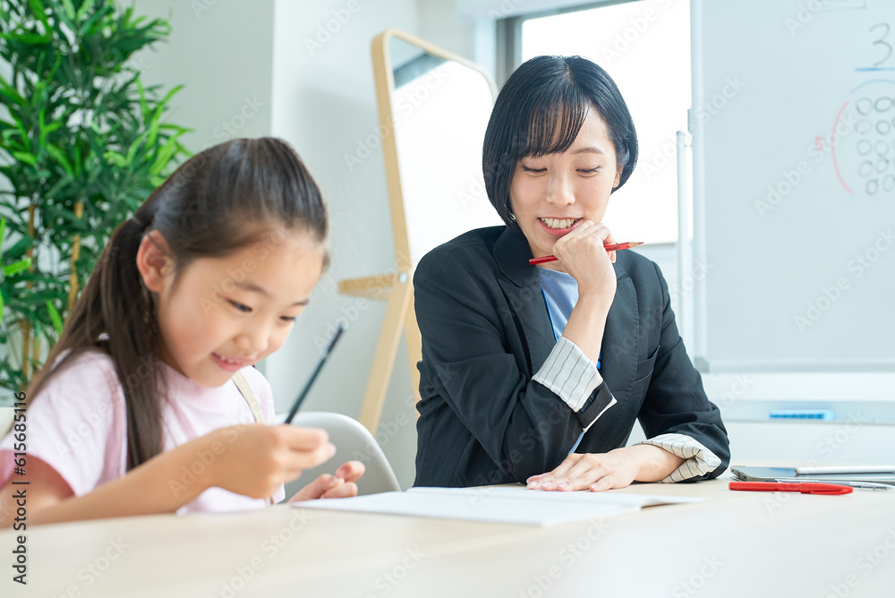 勉強する女の子とサポートするスーツ姿の女性 勉強する女の子とサポートするスーツ姿の女性