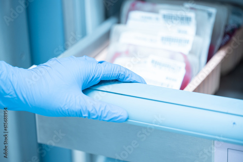 Close up scientist hand holding red blood bag in storage refrigerator at blood bank unit laboratory.Blood bags received from blood donations will be used in patients.Save life medical concept.
