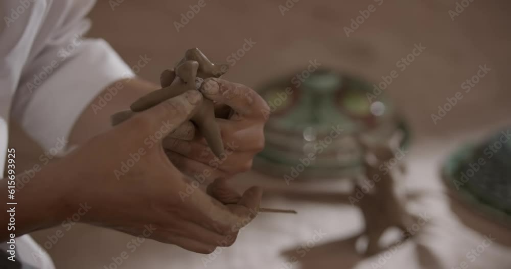 A ceramic artist carves a clay figurine before firing it in his studio A ceramic artist carves a clay figurine before firing it in his studio