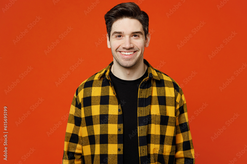 Young smiling happy satisfied positive cheerful caucasian man he wears yellow checkered shirt black t-shirt looking camera isolated on plain red orange background studio portrait. Lifestyle concept.