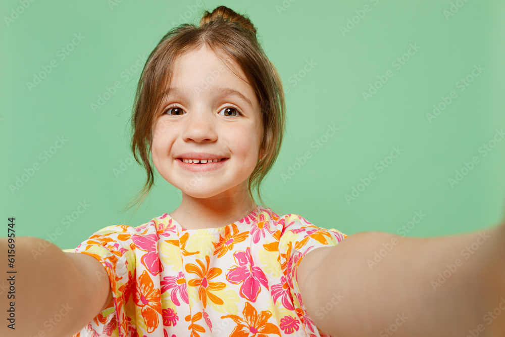 Close up smiling happy little child kid girl 6-7 years old wears casual clothes have fun do selfie shot pov on mobile cell phone isolated on plain green background. Mother's Day love family concept. Close up smiling happy little child kid girl 6-7 years old wears casual clothes have fun do selfie shot pov on mobile cell phone isolated on plain green background. Mother's Day love family concept.